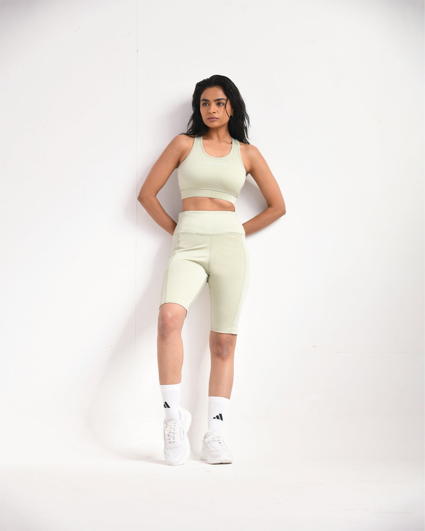 Full pose of a woman wearing light sage training shorts and a sports bra by Six Point Three, designed for high-performance workouts and active lifestyles.