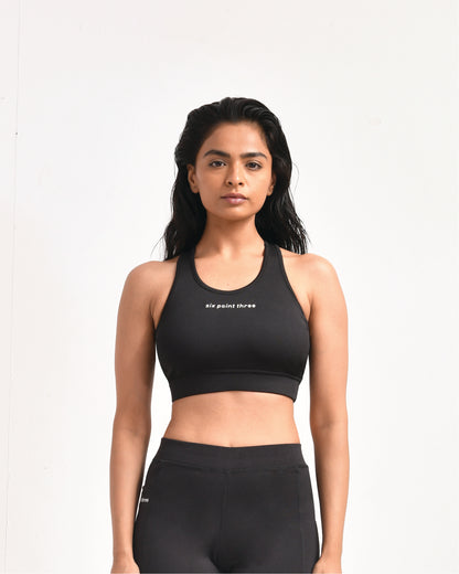 Woman wearing black high-compression sports bra with Six Point Three logo, ideal for intense workouts, featuring racerback design and moisture-wicking fabric for maximum support and comfort.