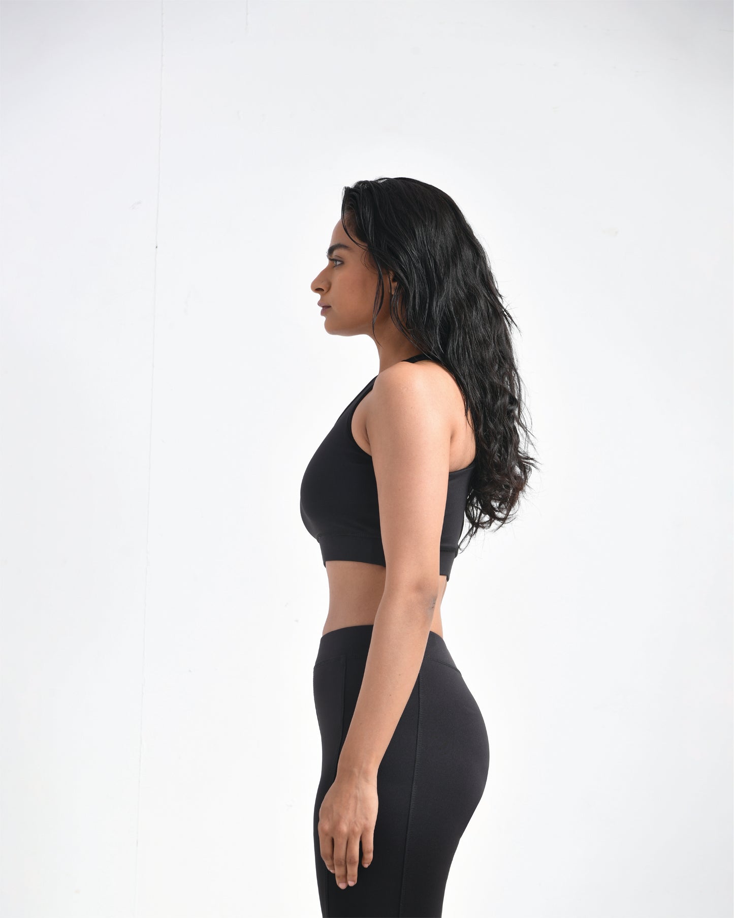 Side view of woman wearing black sports bra for women for gym workouts, featuring high support sports bra for large breasts, paired with stylish gym wear ideal for high-intensity workouts.