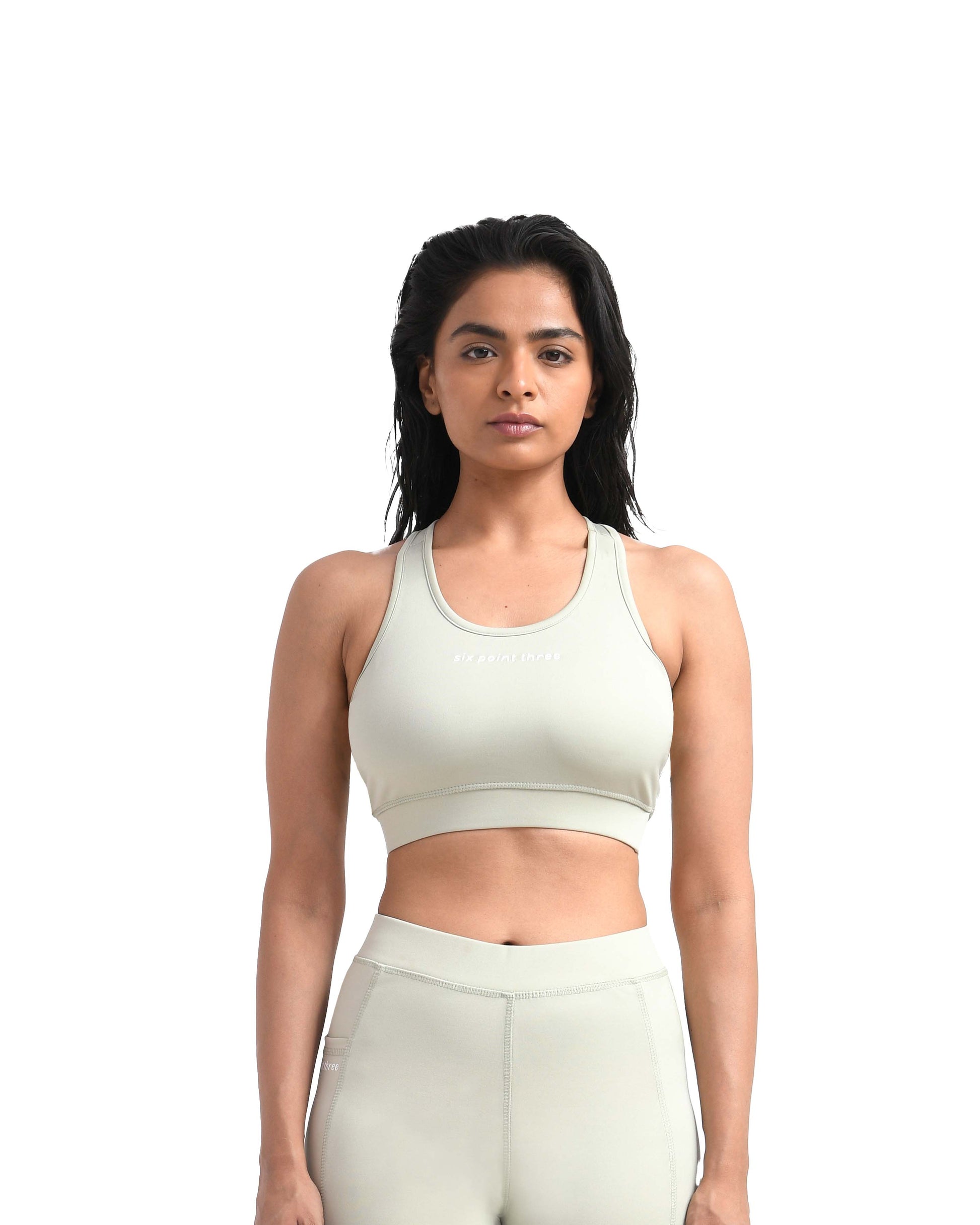 Front view of a woman wearing a light green gym sports bra with a racerback design, perfect for high-intensity workouts and stylish gym wear, by Six Point Three