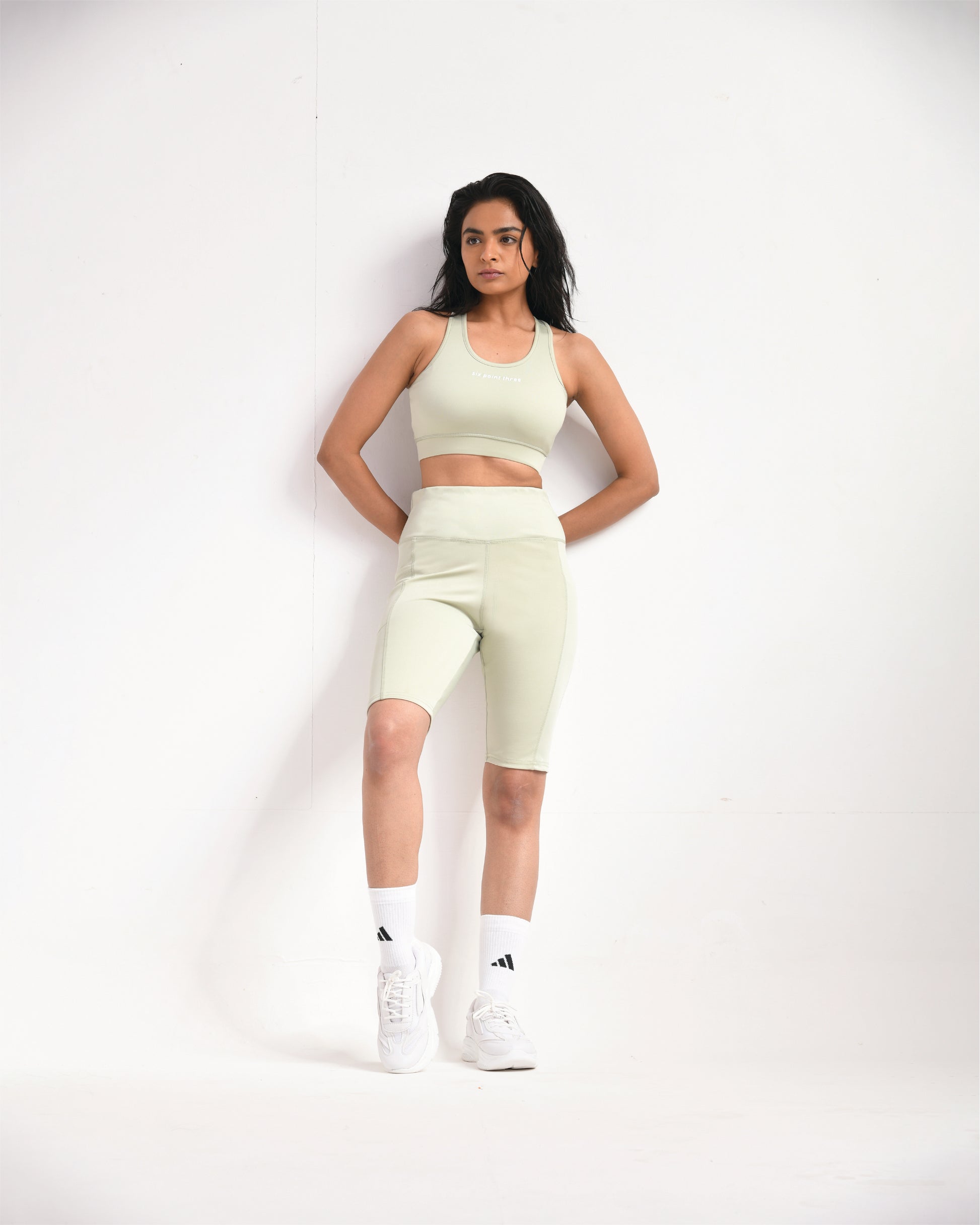 Full pose of a woman wearing light sage training shorts and a sports bra by Six Point Three, designed for high-performance workouts and active lifestyles.