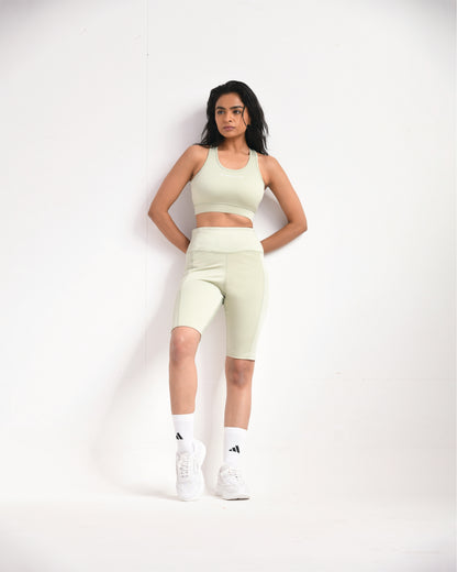 Full pose of a woman wearing light sage training shorts and a sports bra by Six Point Three, designed for high-performance workouts and active lifestyles.